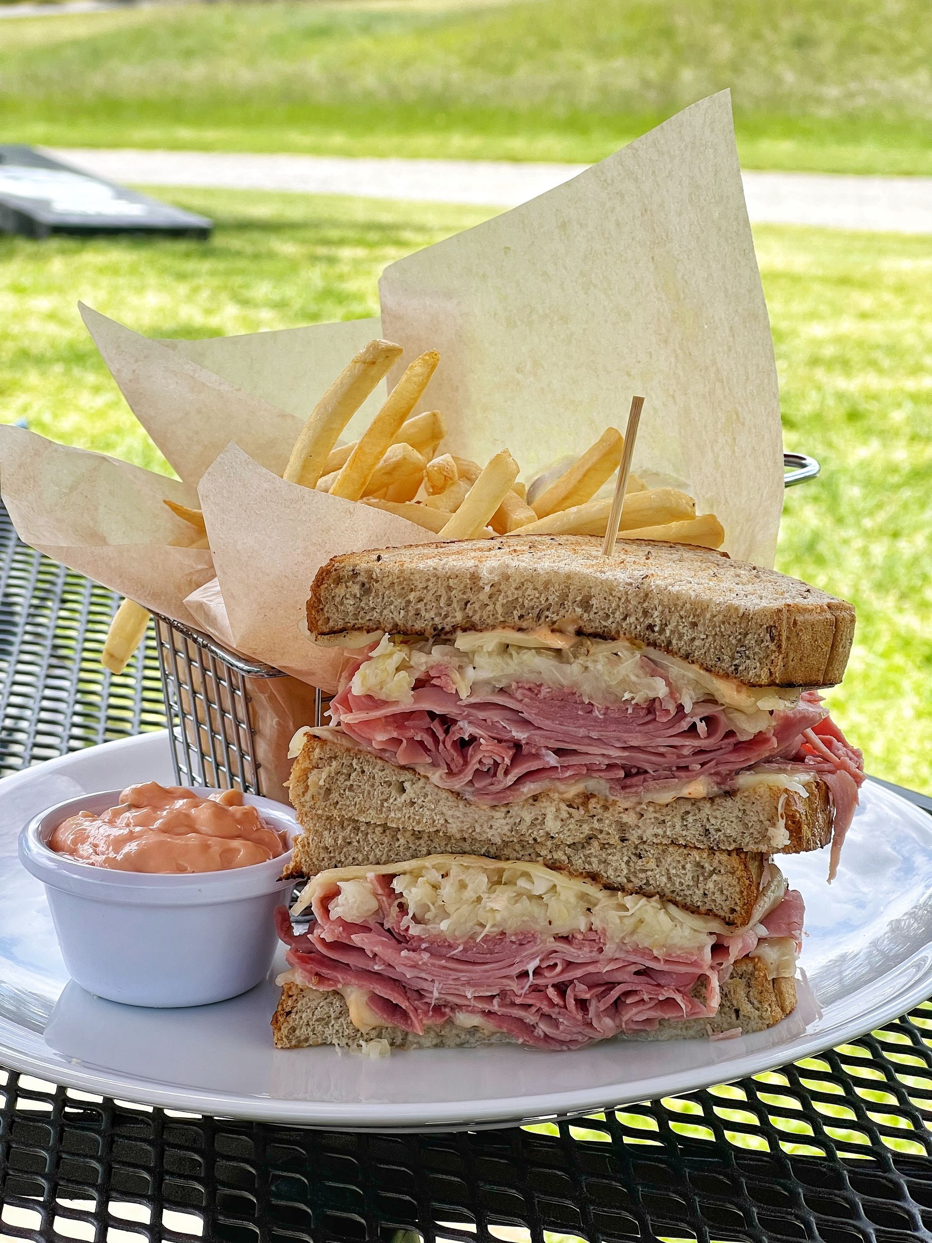 A sandwich and french fries are on a plate on a table.