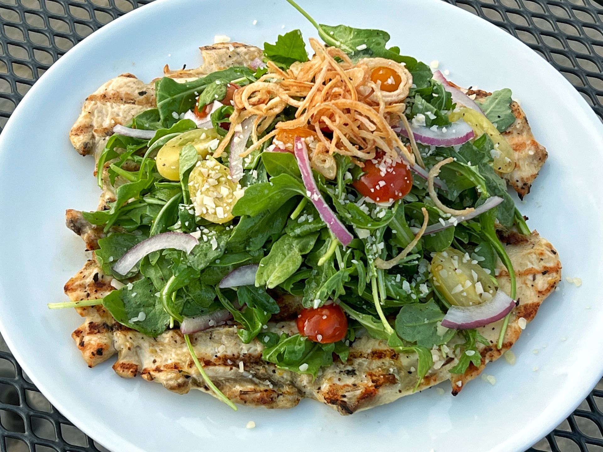 A white plate topped with meat and vegetables on a table