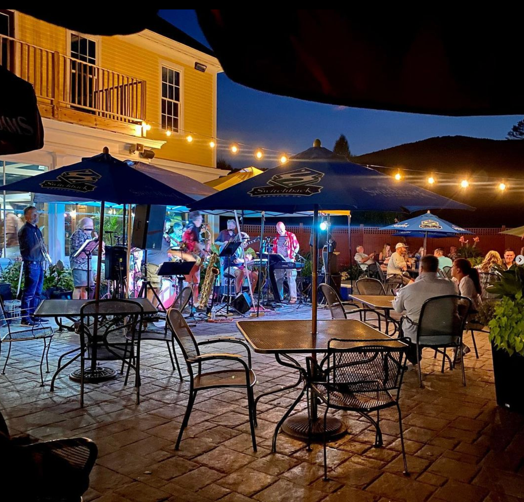 A group of people are sitting under umbrellas at a restaurant