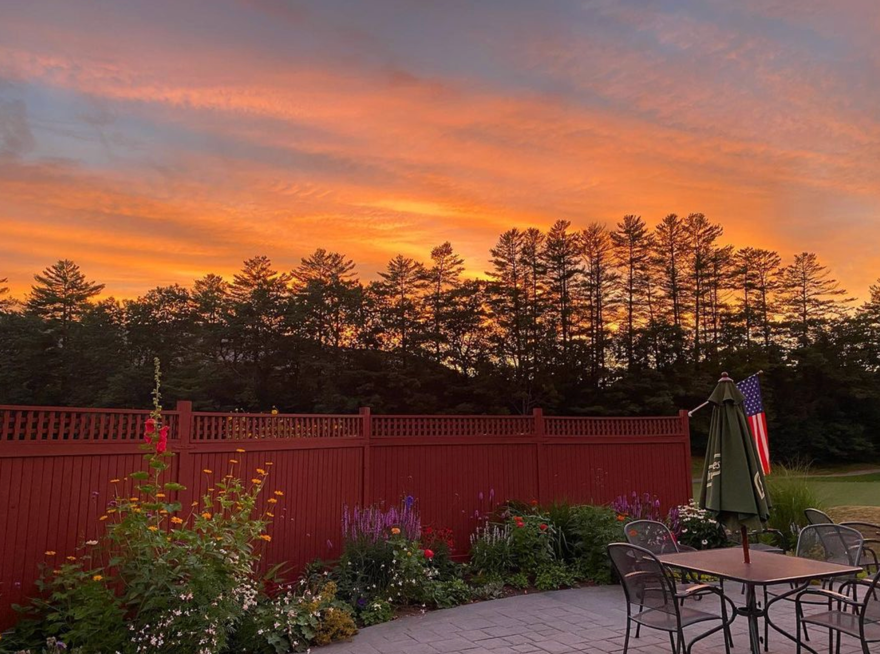 A patio with a table and chairs and a sunset in the background.