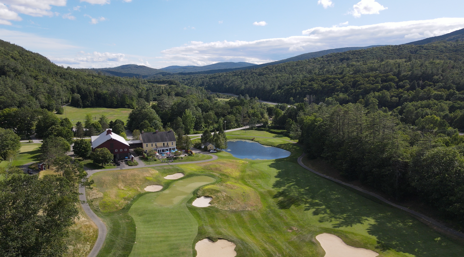 An aerial view of a golf course surrounded by trees and mountains.