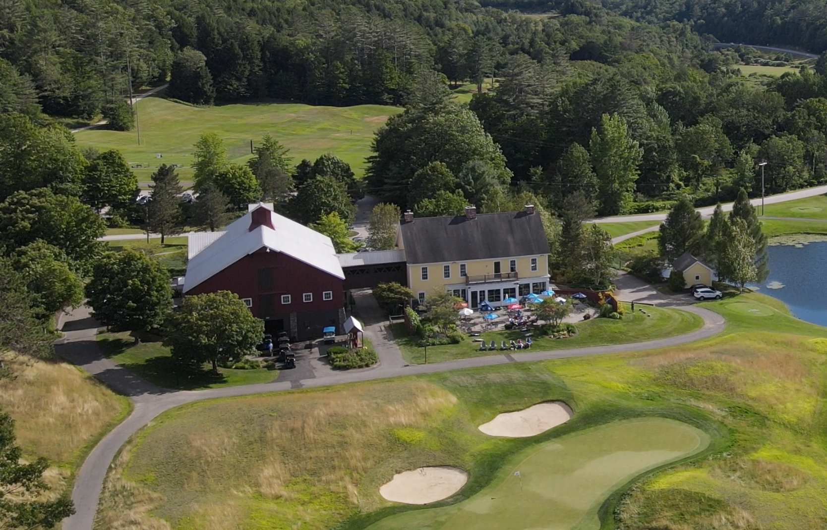 An aerial view of a golf course with a barn in the background