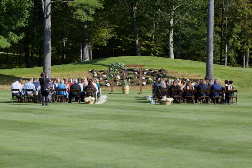 A group of people are sitting at tables on a golf course.
