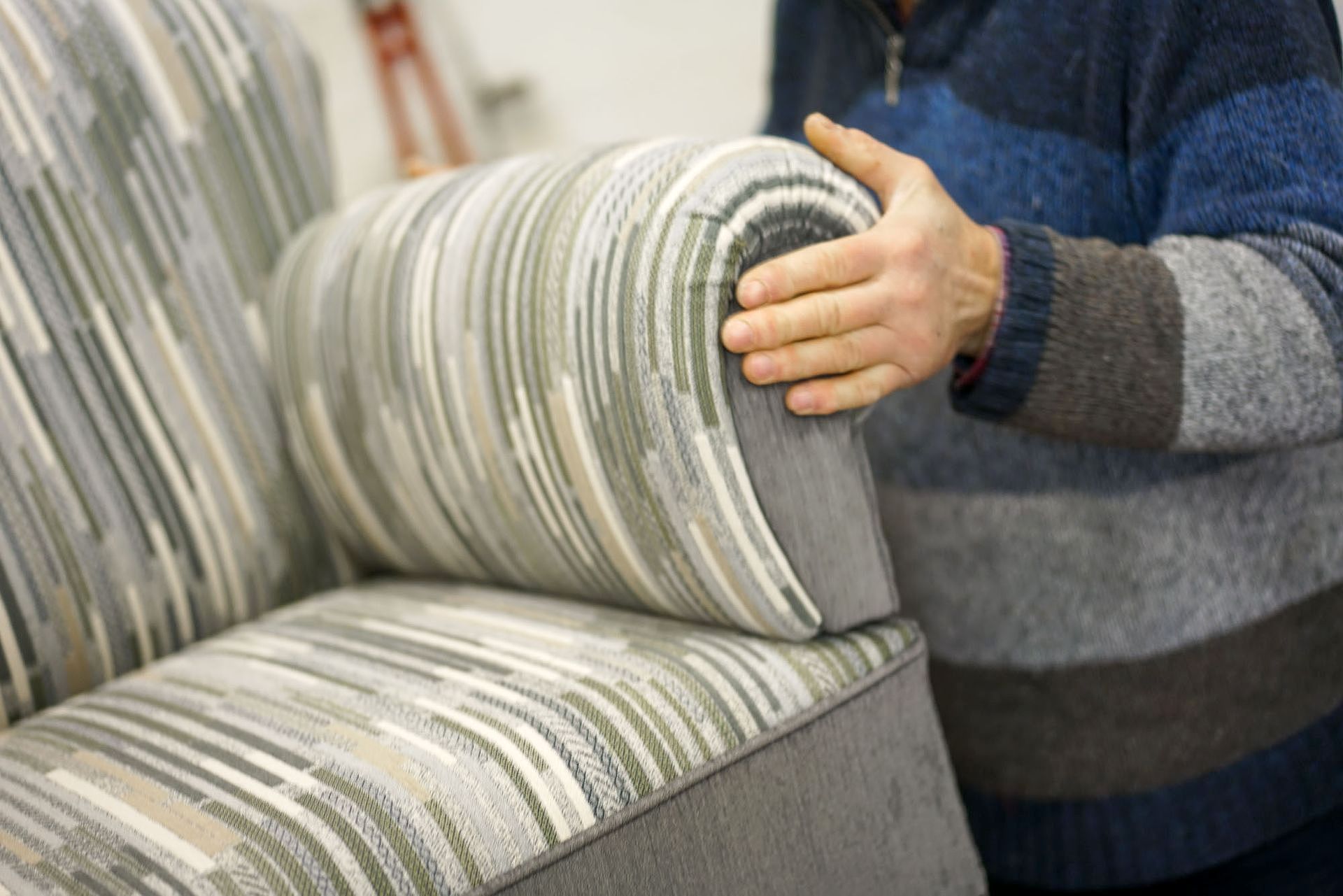 Ein Mann hält die Armlehne eines Sofas