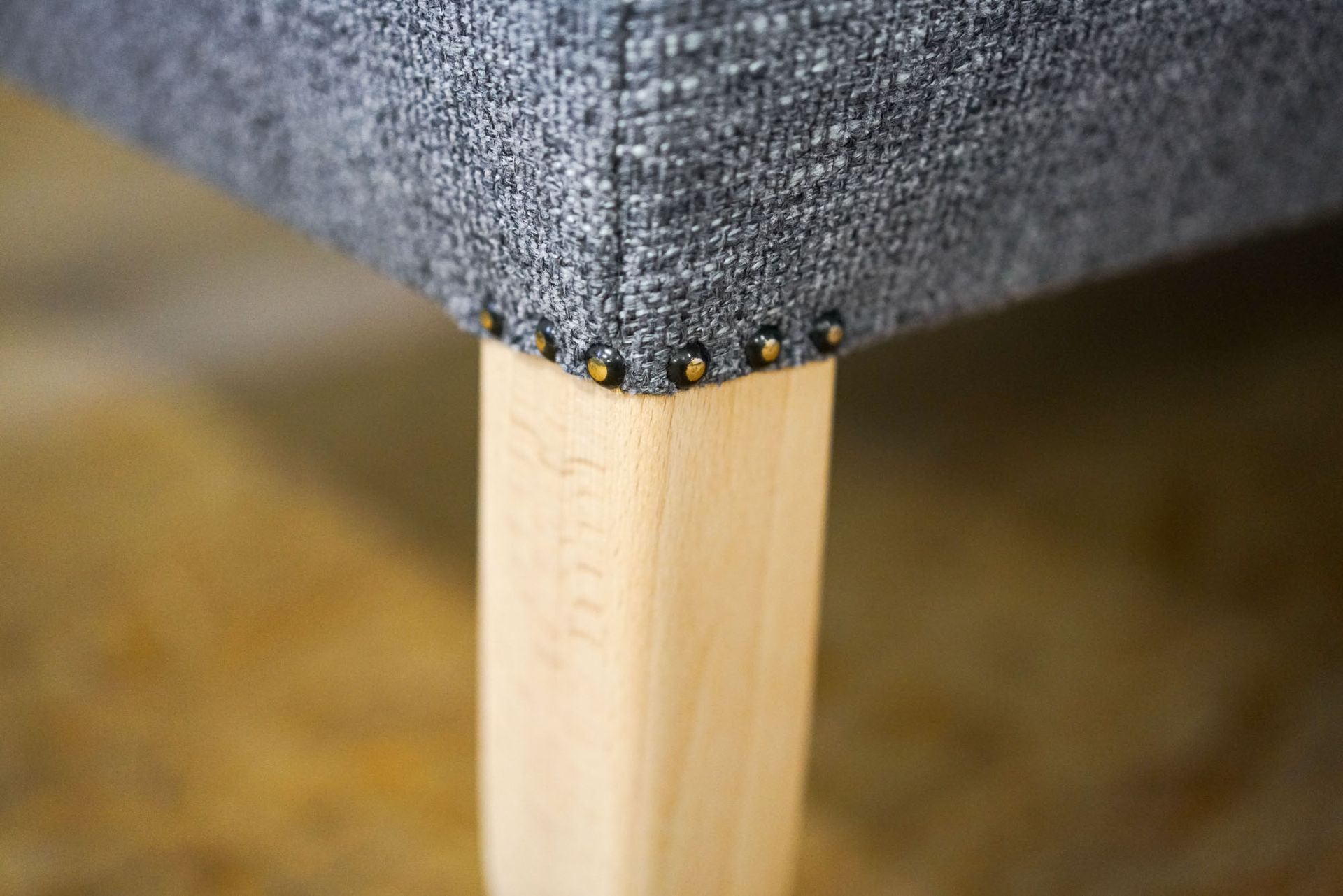 Eine Nahaufnahme des Beins einem grauen Sofa mit Holzbeinen