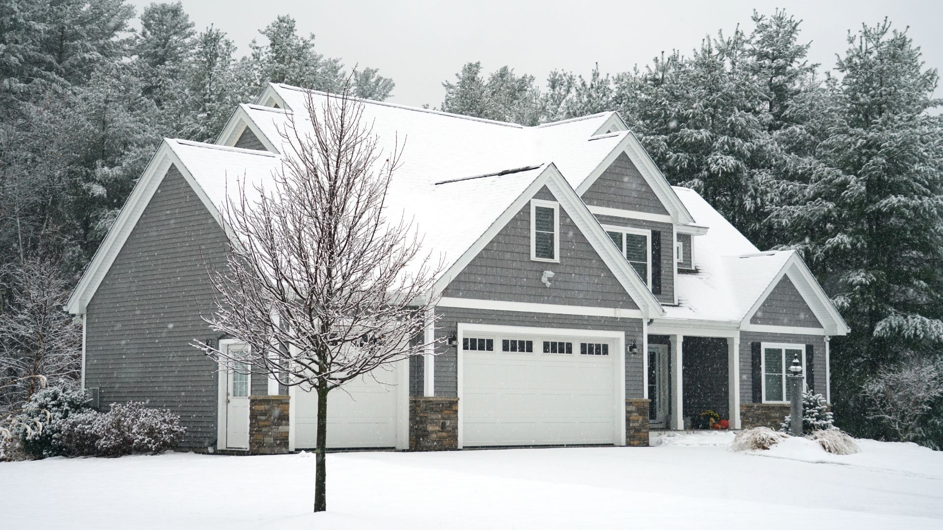 A house with a white garage door is covered in snow.