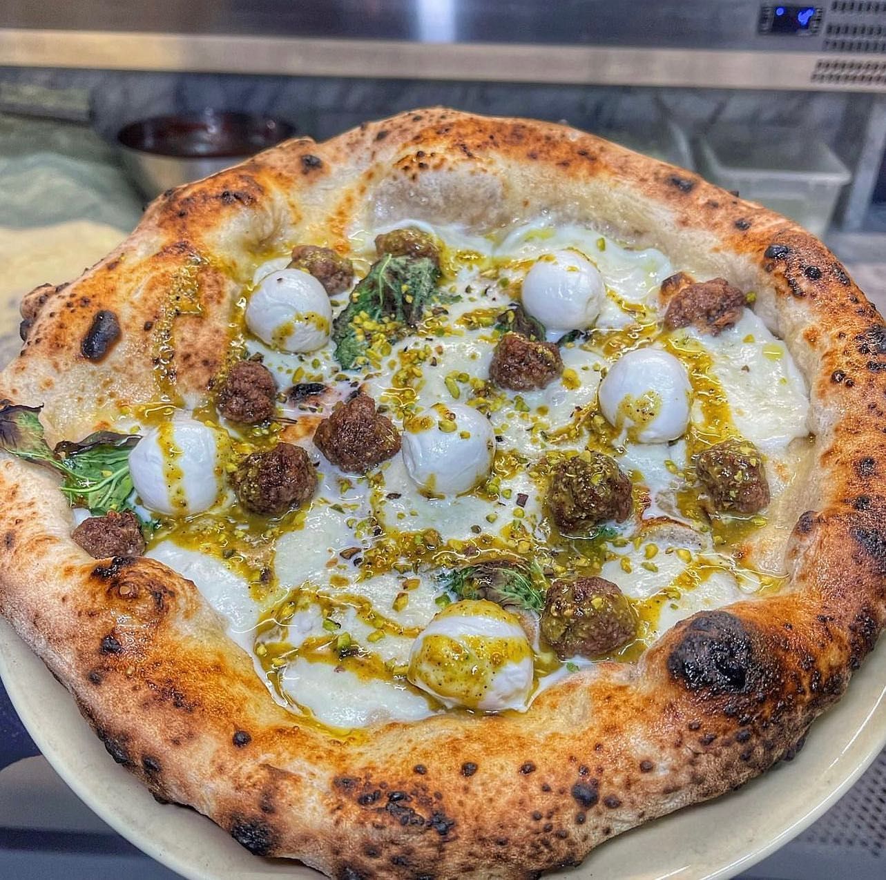 Una pizza con tanti condimenti è su un piatto.