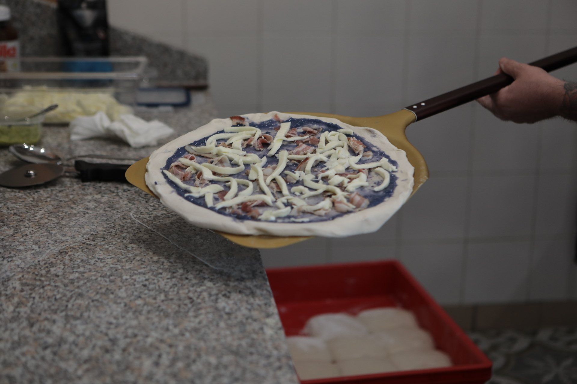 Una persona tiene una pizza su una spatola di legno.