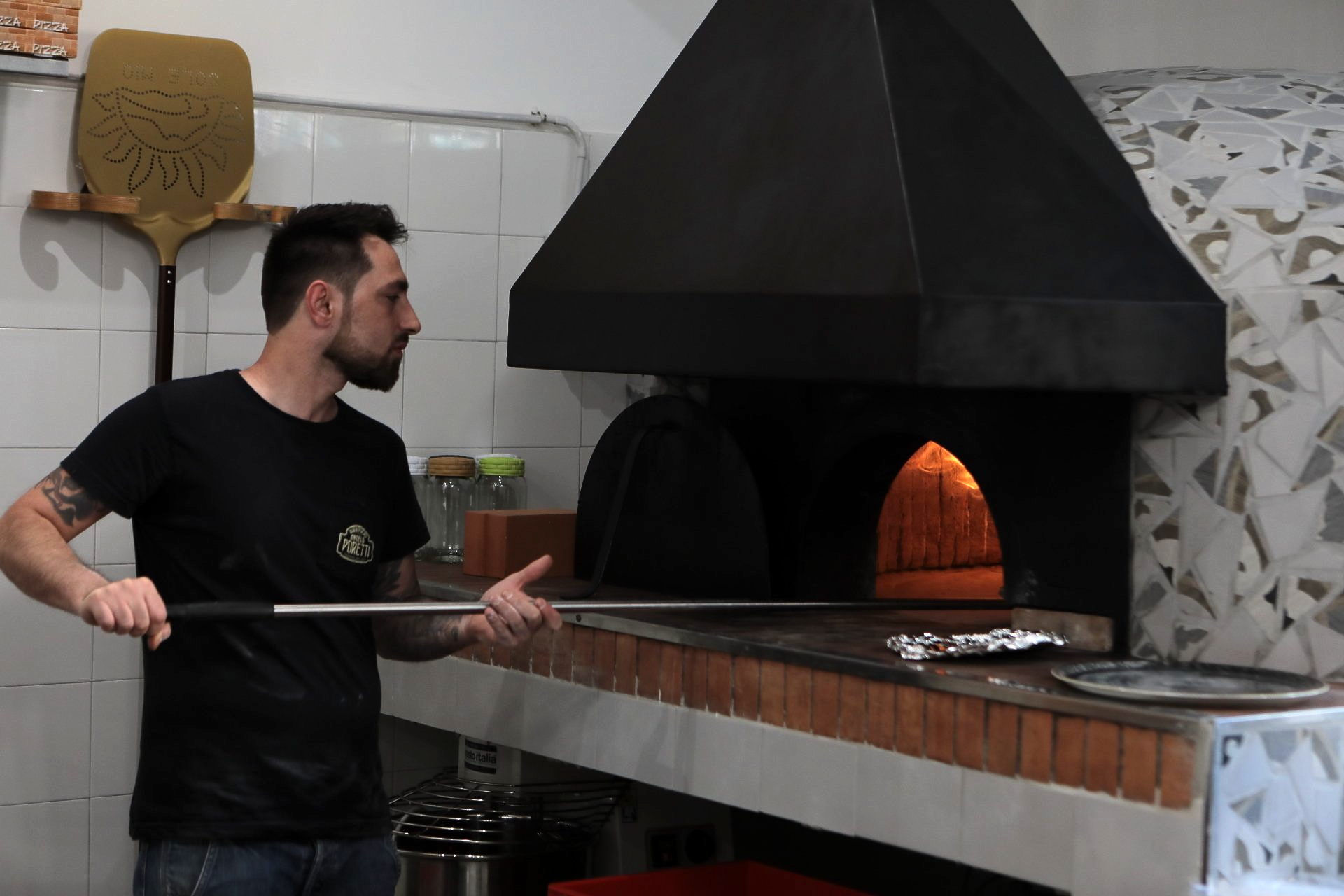 Un uomo sta mettendo una pizza in un forno per pizza