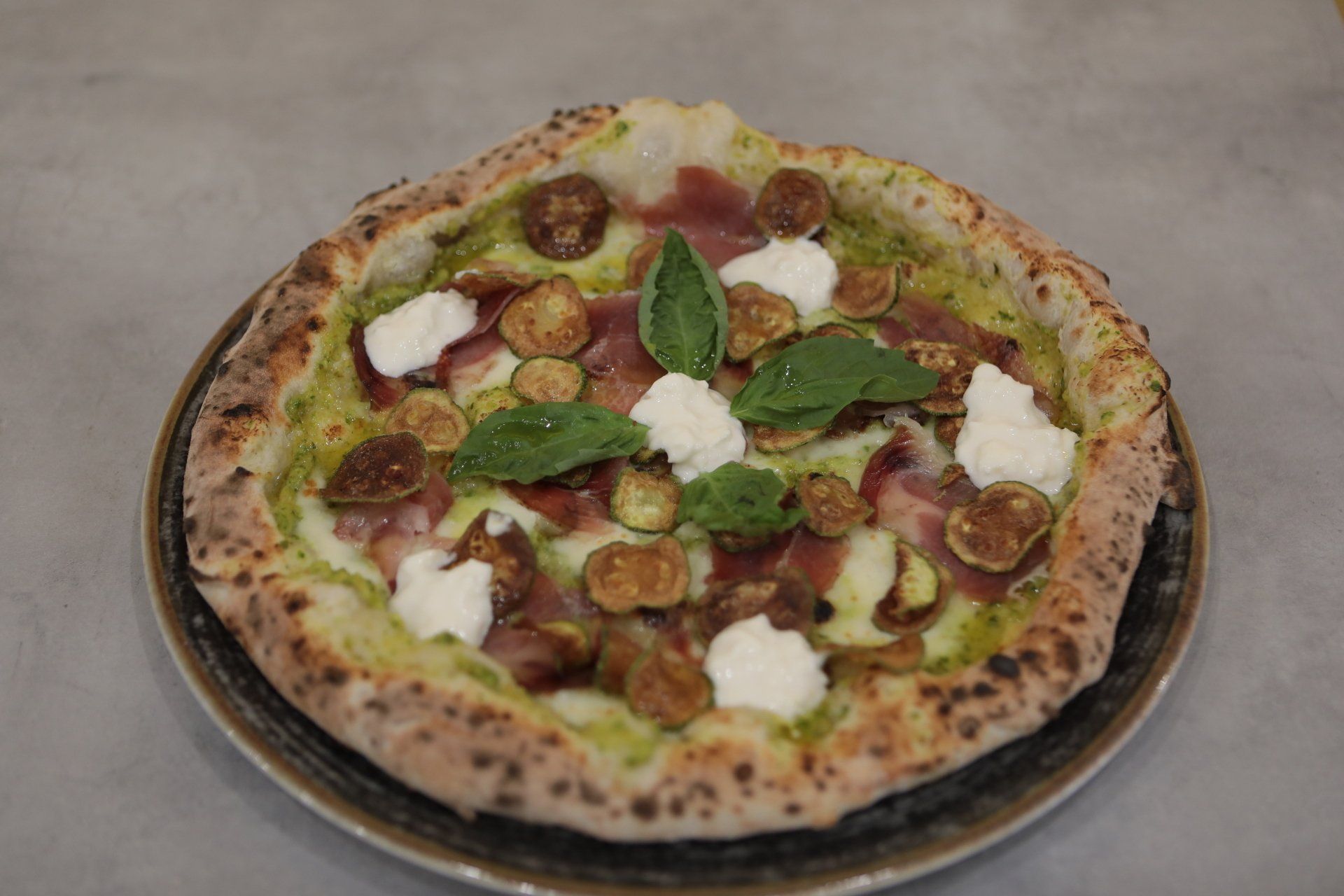 Una pizza è appoggiata su un piatto su un tavolo.