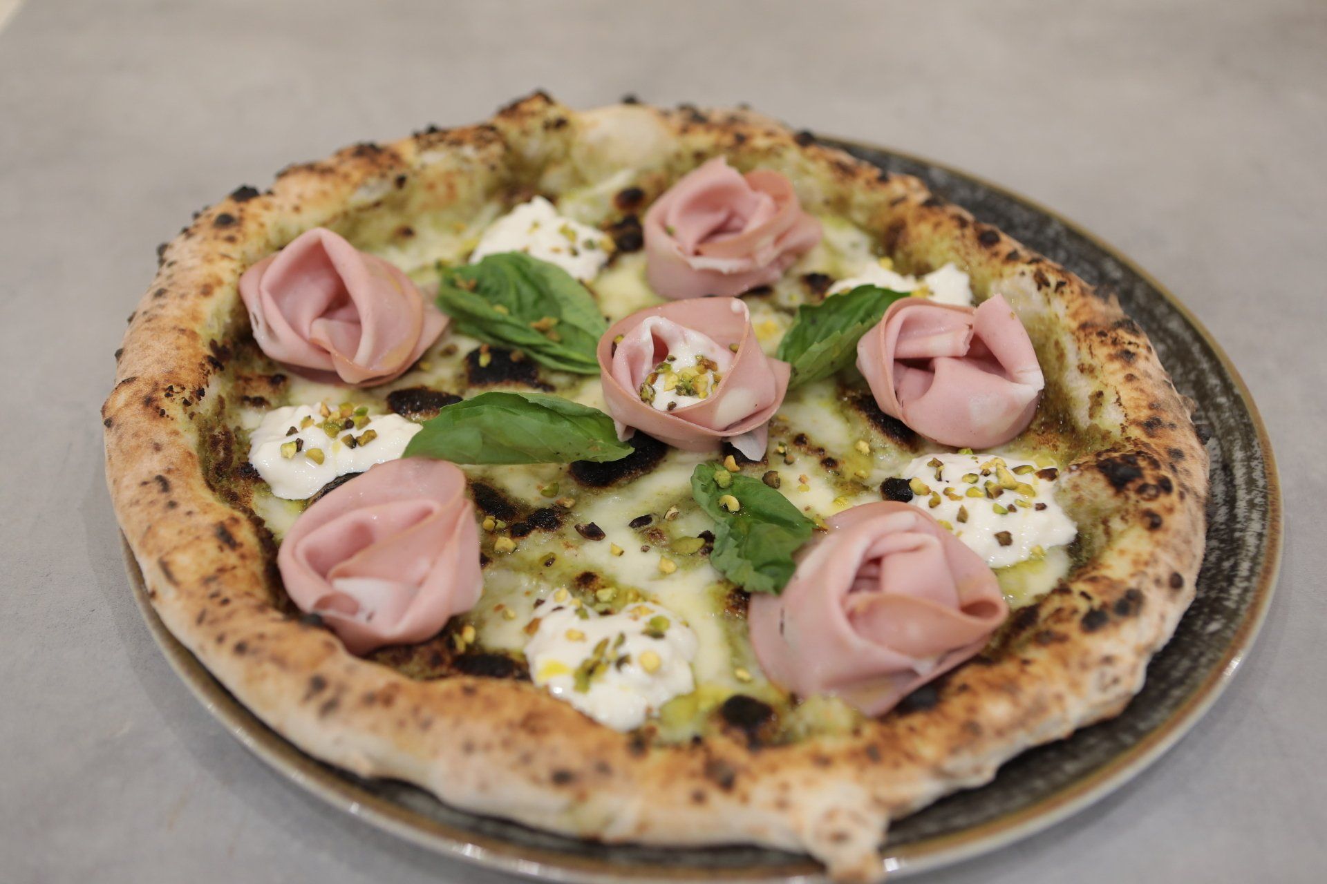 Una pizza con prosciutto e formaggio su un piatto su un tavolo.