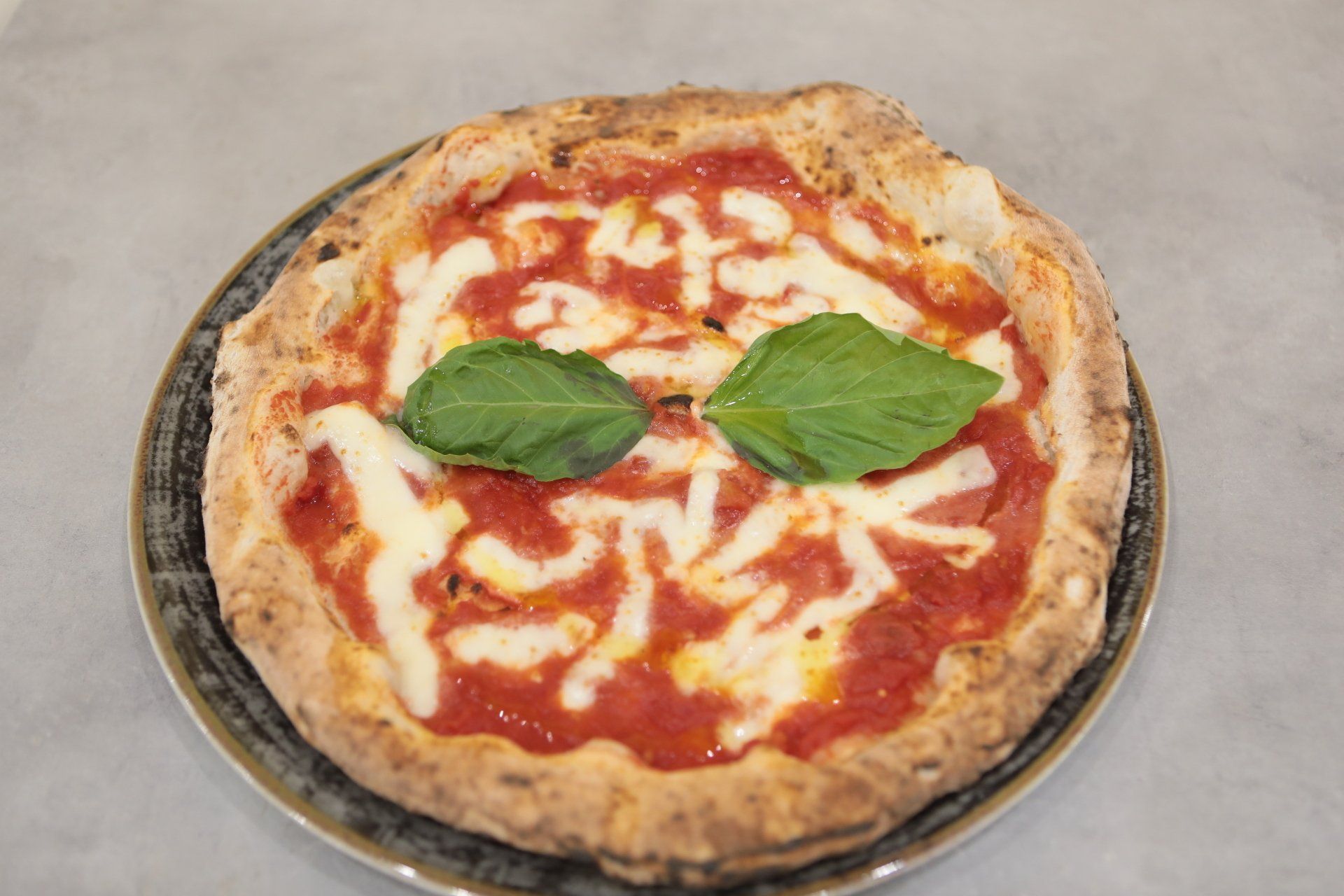 Una pizza con salsa di pomodoro, formaggio e basilico su un piatto.