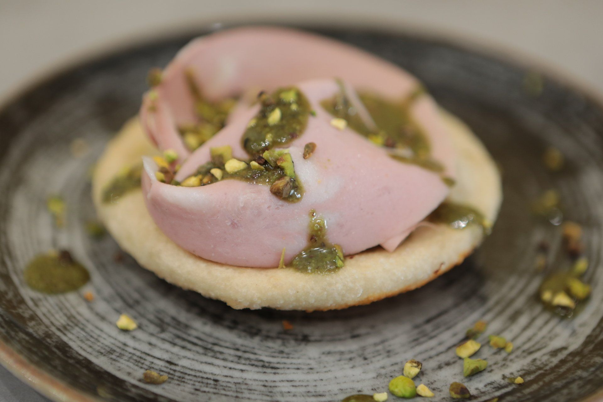 Primo piano di un panino su un piatto con pistacchi.