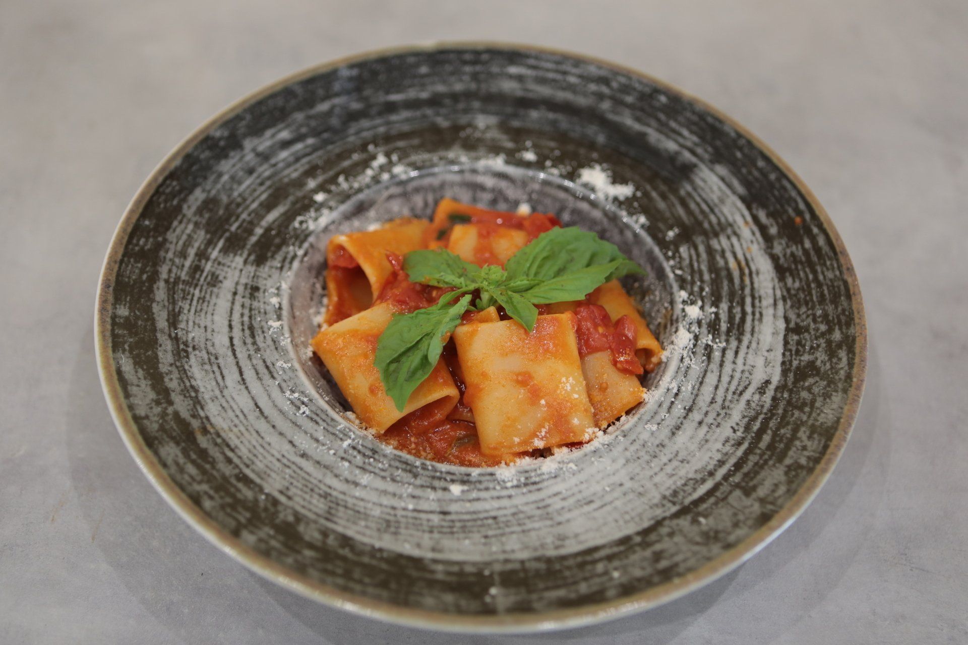 Un piatto di pasta con sugo di pomodoro e basilico su un tavolo.