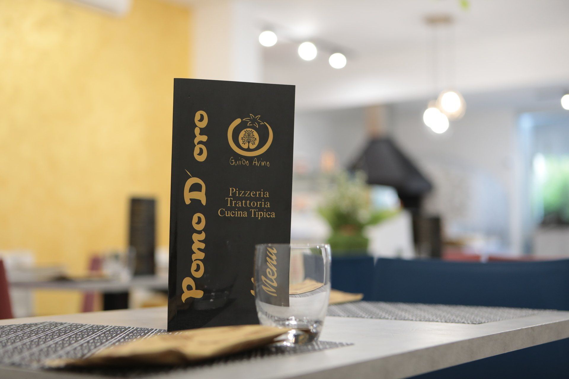 Un menù è appoggiato su un tavolo accanto a un bicchiere.