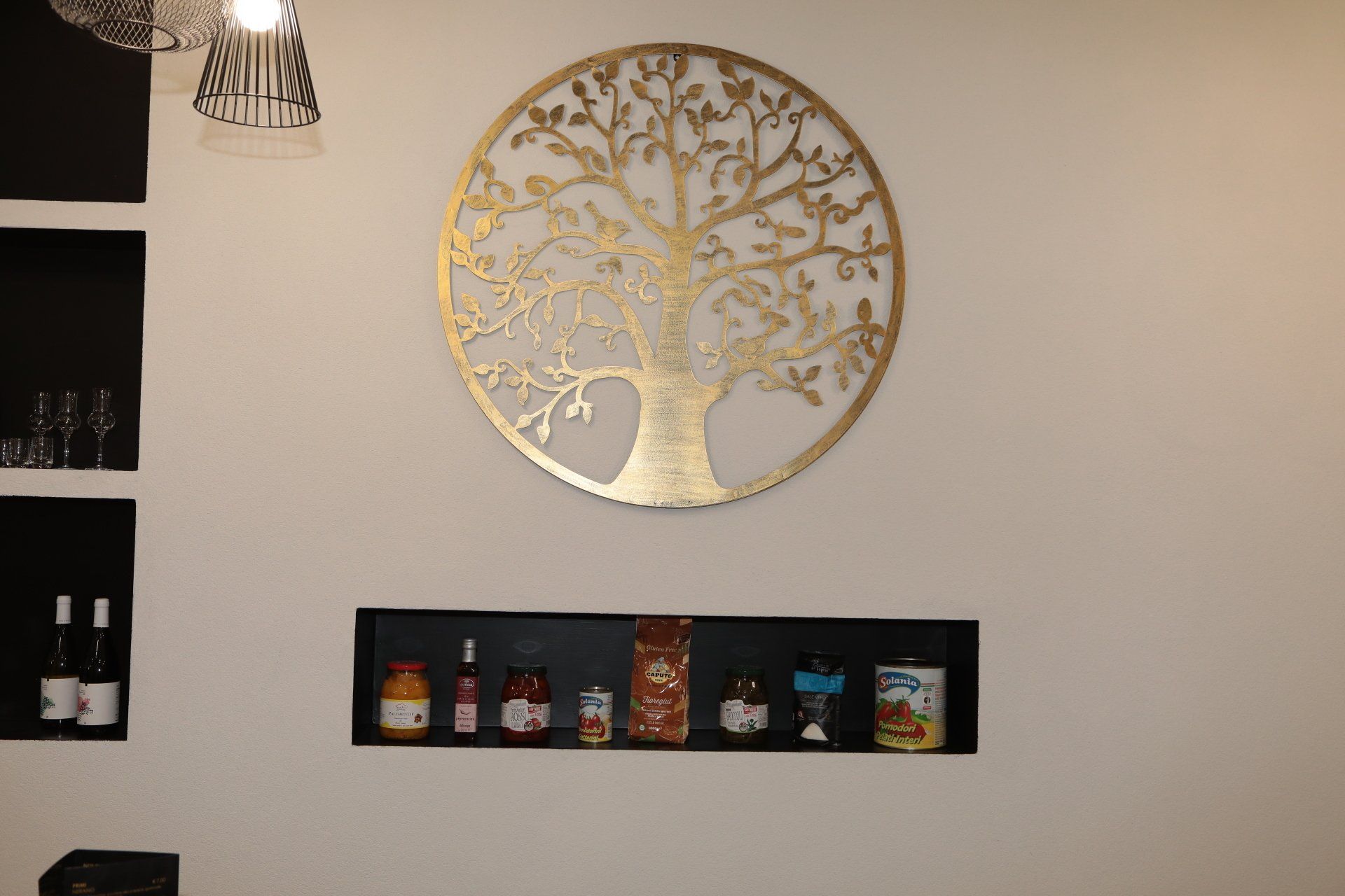 Un muro con un albero sopra e uno scaffale con dei barattoli sopra