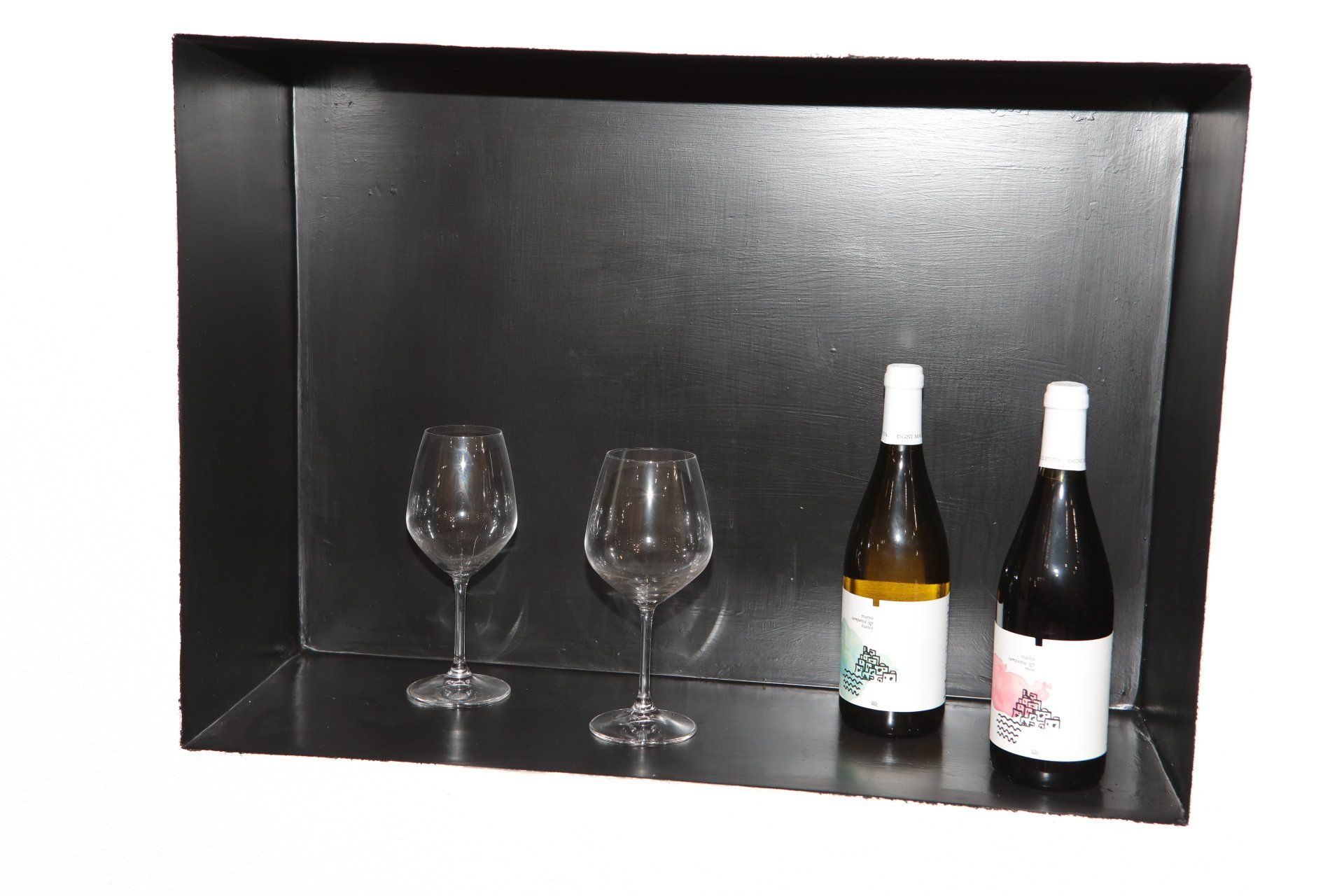 Due bottiglie di vino e due bicchieri di vino su uno scaffale nero