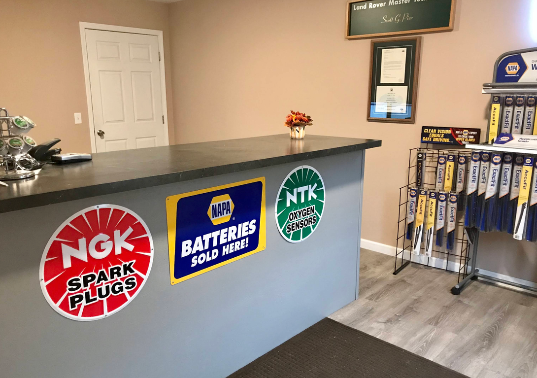 Auto parts store counter with NGK, Interstate Batteries, and NTK logos on the front | Discovery Automotive