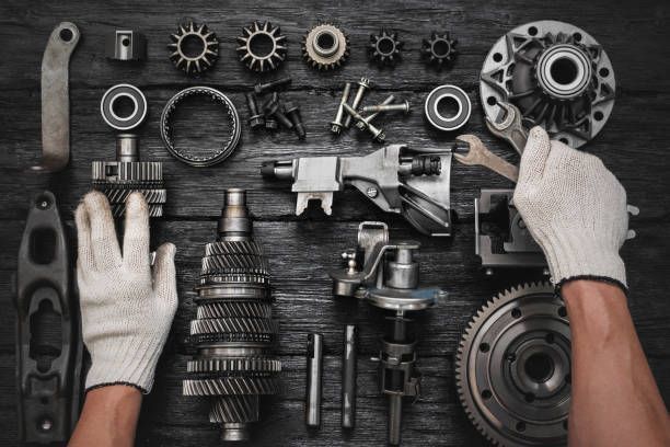 Mechanic organizing auto parts on a dark surface, featuring gears, bolts, and tools at Crabtree Auto