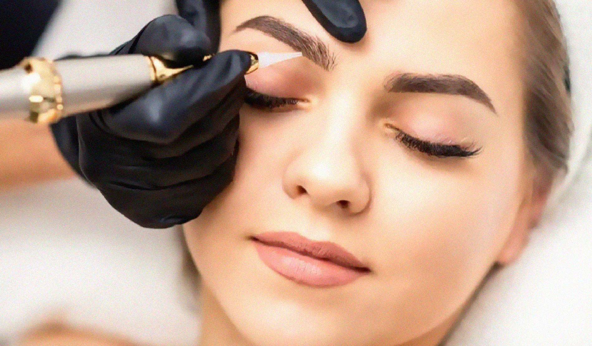 Eine Frau lässt sich ein permanentes Augenbrauen-Tattoo auf die Augenbrauen stechen.