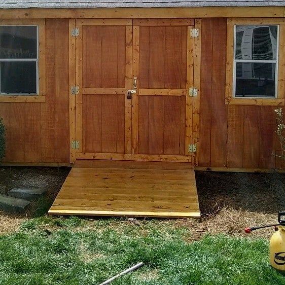 A wooden shed with a wooden deck in front of it.