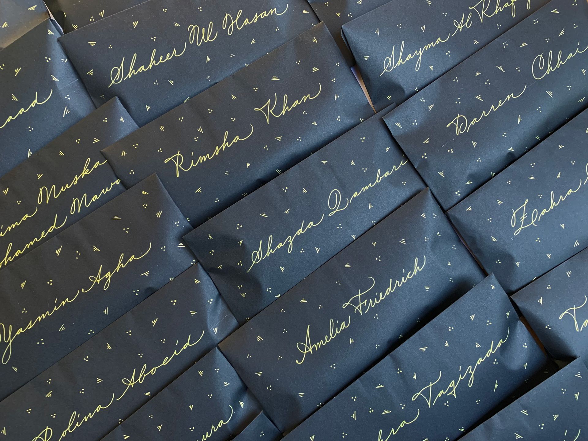 Stacked dark blue gift boxes with gold cursive writing and starry confetti accents