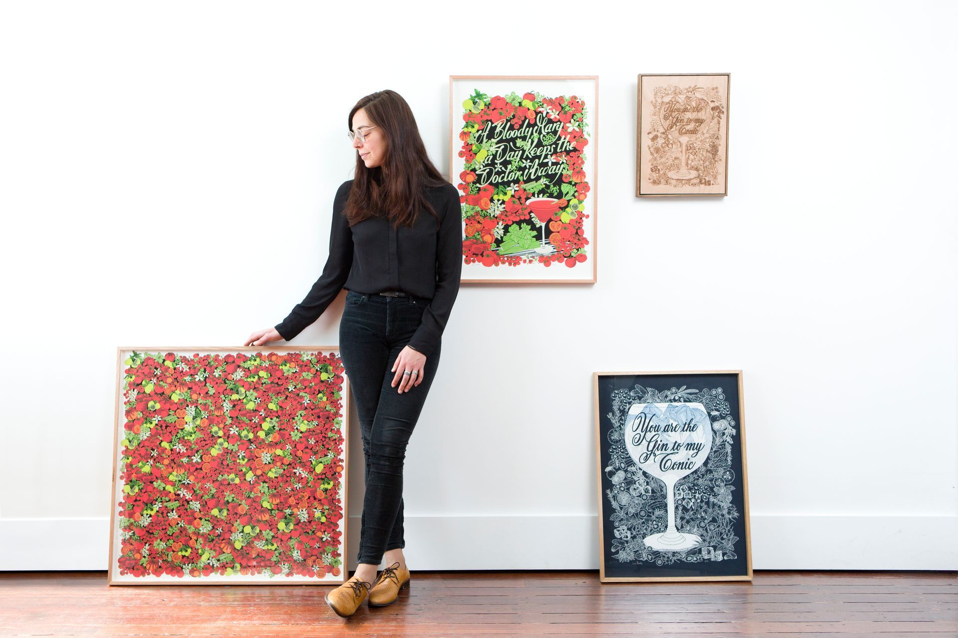 Maria Montes standing beside colorful abstract paintings displayed against a white gallery wall.