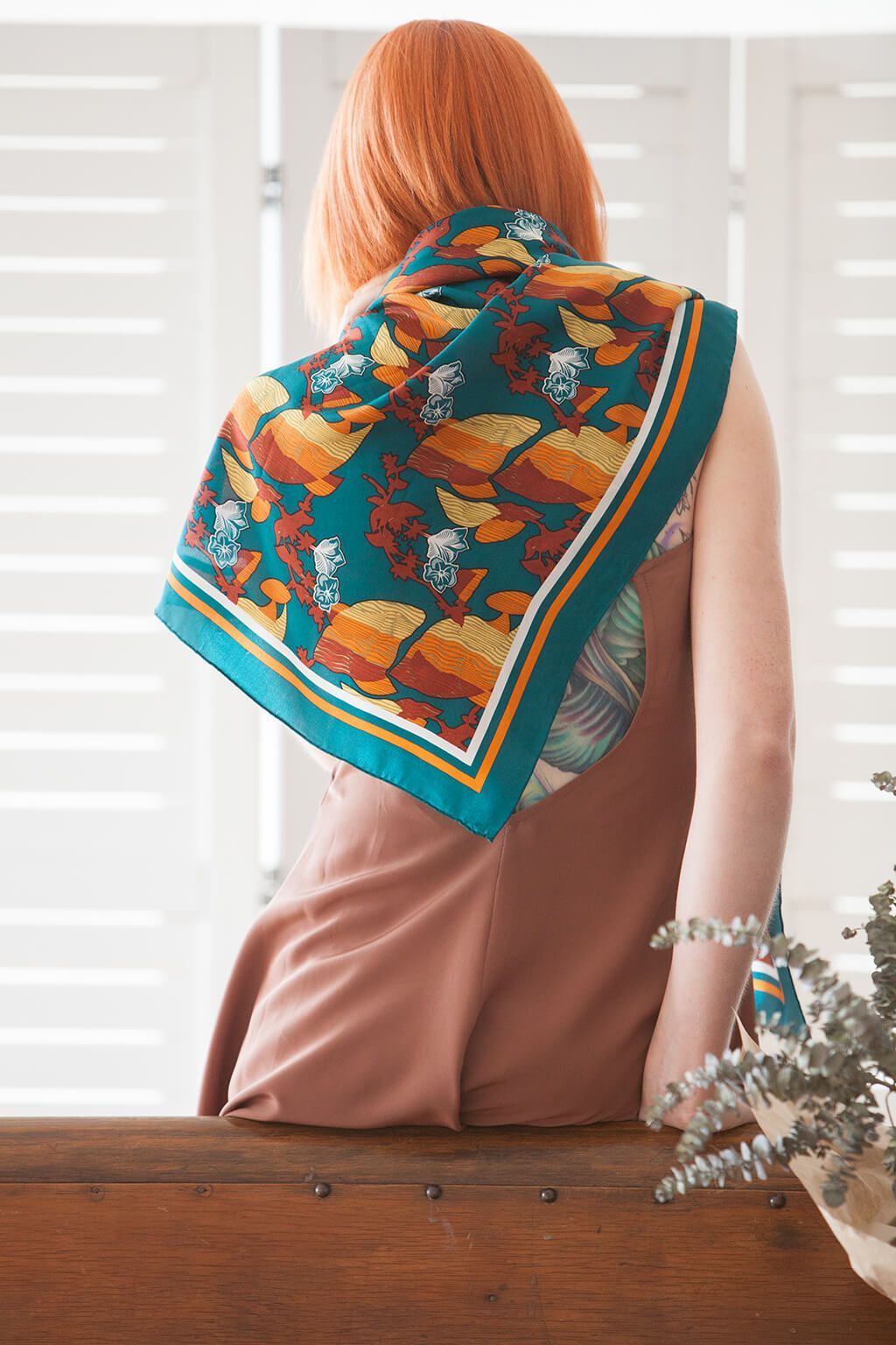 Person seated by a window, showing a colorful patterned scarf draped over their shoulders