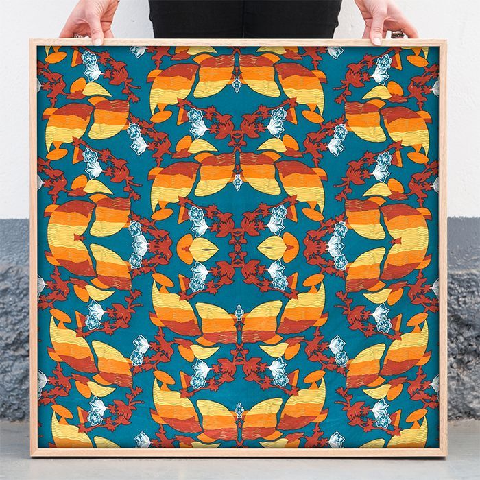 Colorful abstract floral fabric art in a wooden frame, with bold orange, blue, and red mirrored patterns