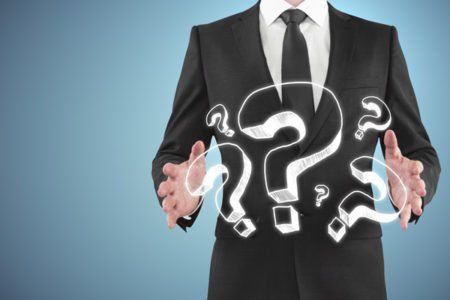 Man in a suit gesturing to imaginary questions marks floating in front of him