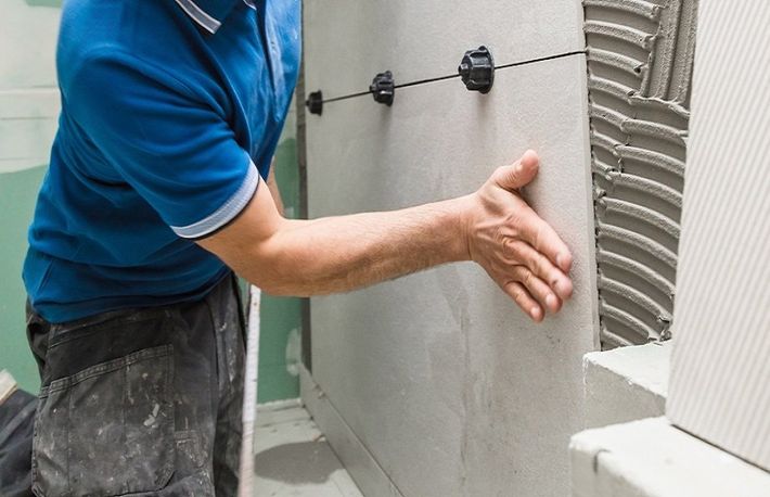 Bathroom renovator installing bathroom tiles for a commercial washroom in in Wollongong, NSW.