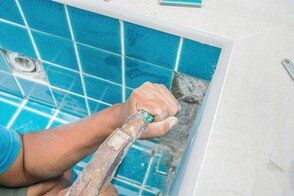 pool service contractor repairing pool tiles