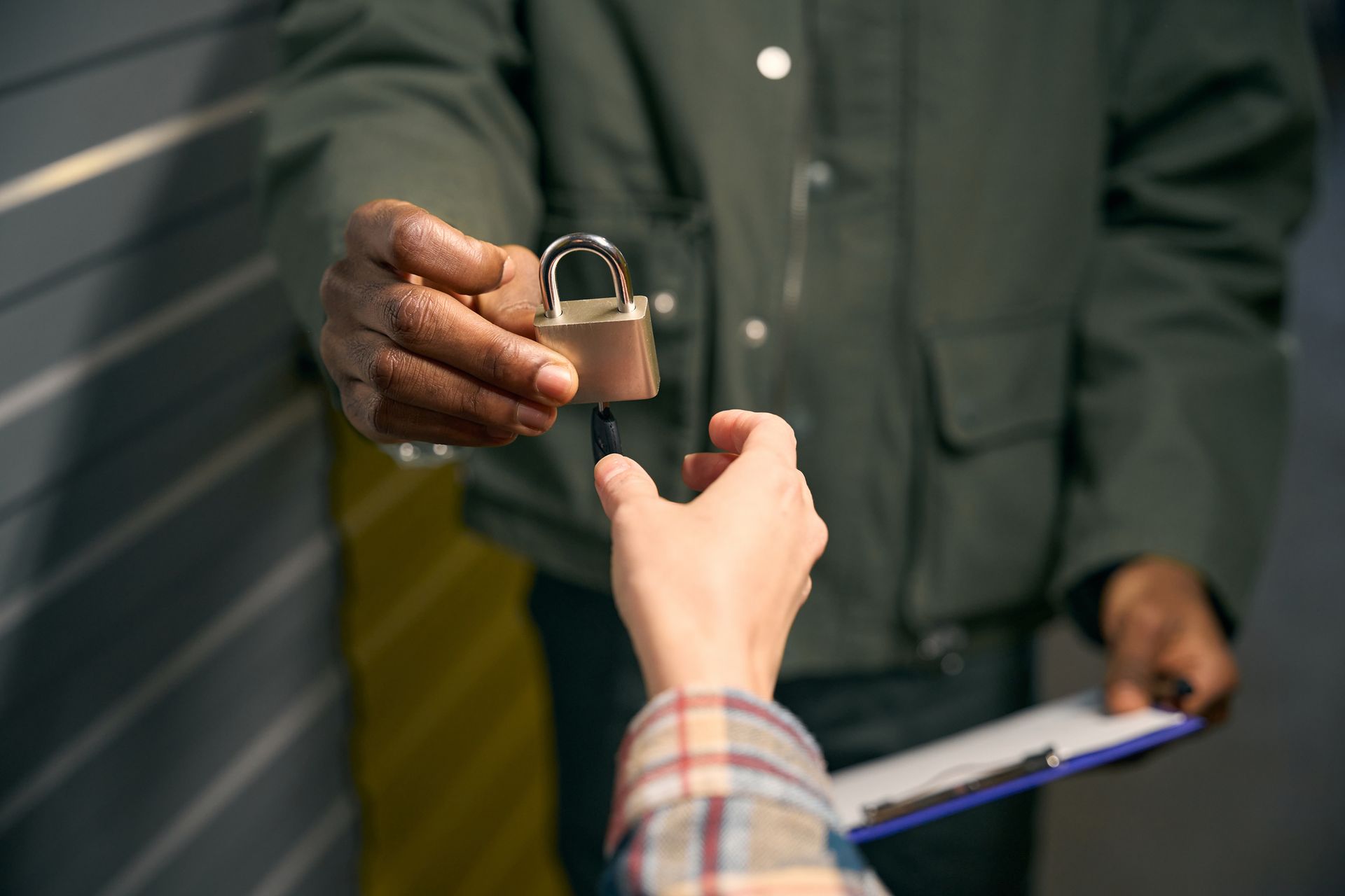 Person handing a padlock key to another person.