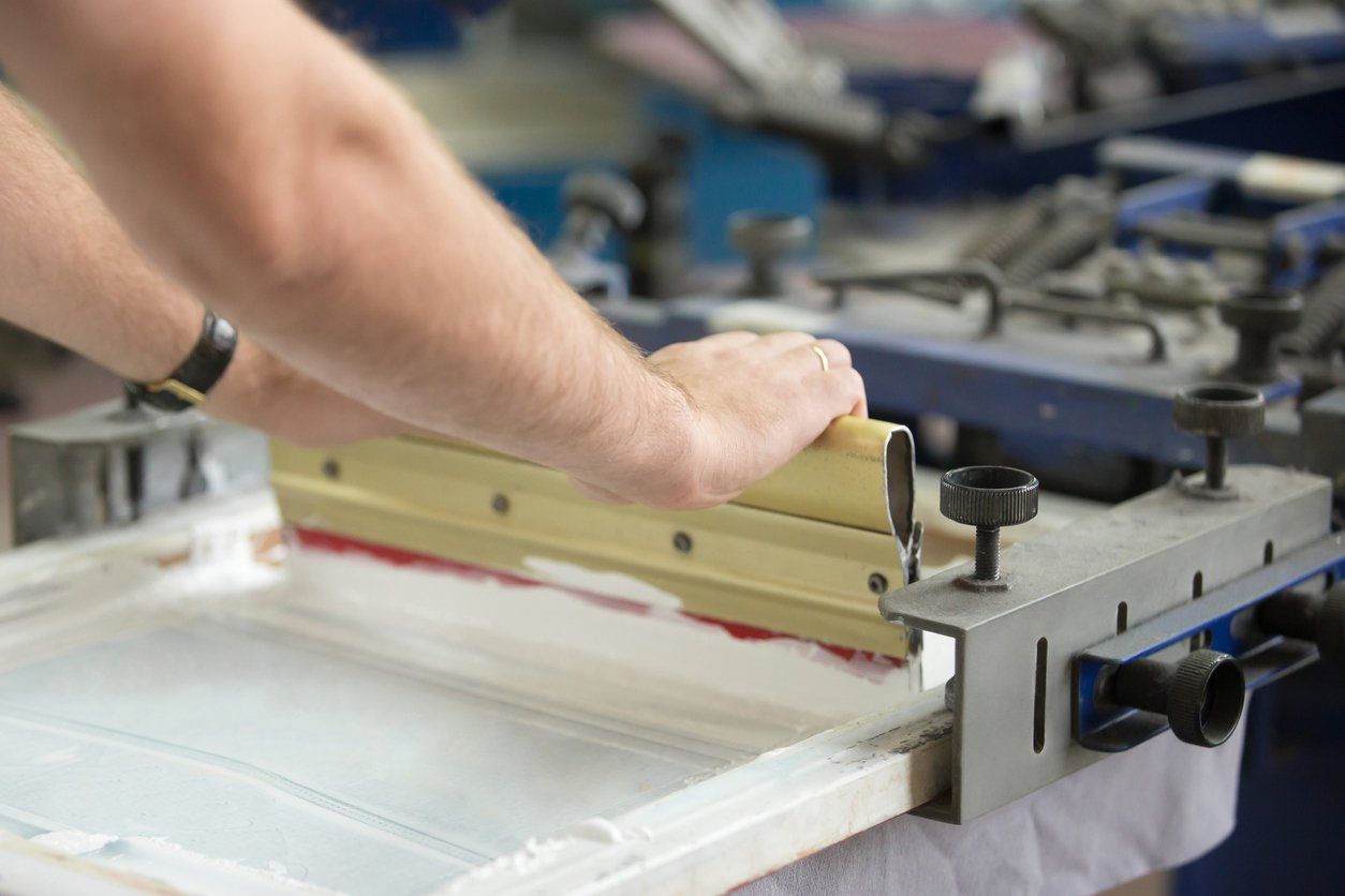 Man working for 20 Days Printing, setting up the equipment for a custom t-shirt printing.