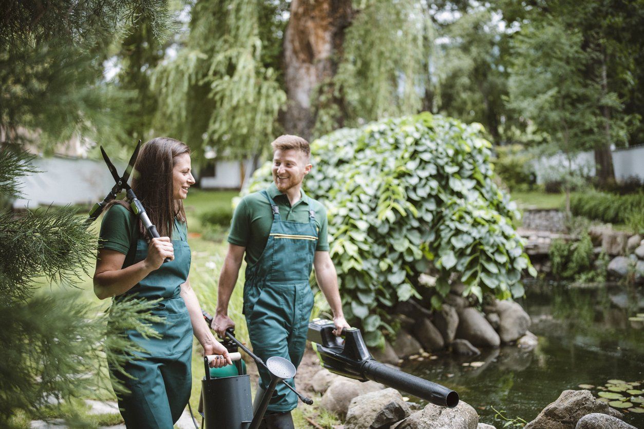 Two landscape workers wearing green overalls as they're about to work on a project - showing uniform