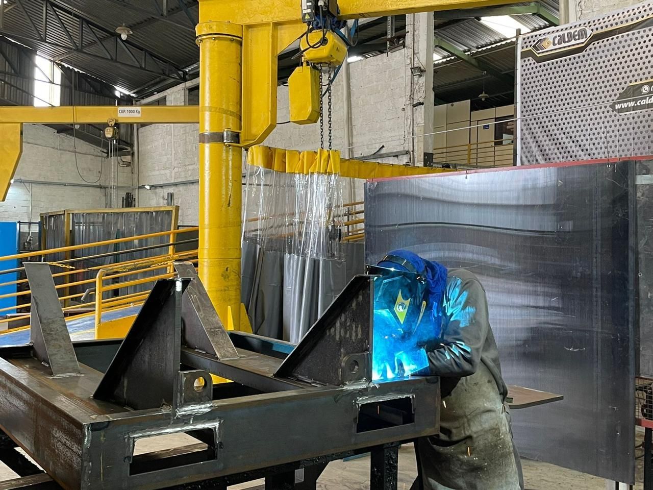 Um homem está soldando um pedaço de metal em uma fábrica.