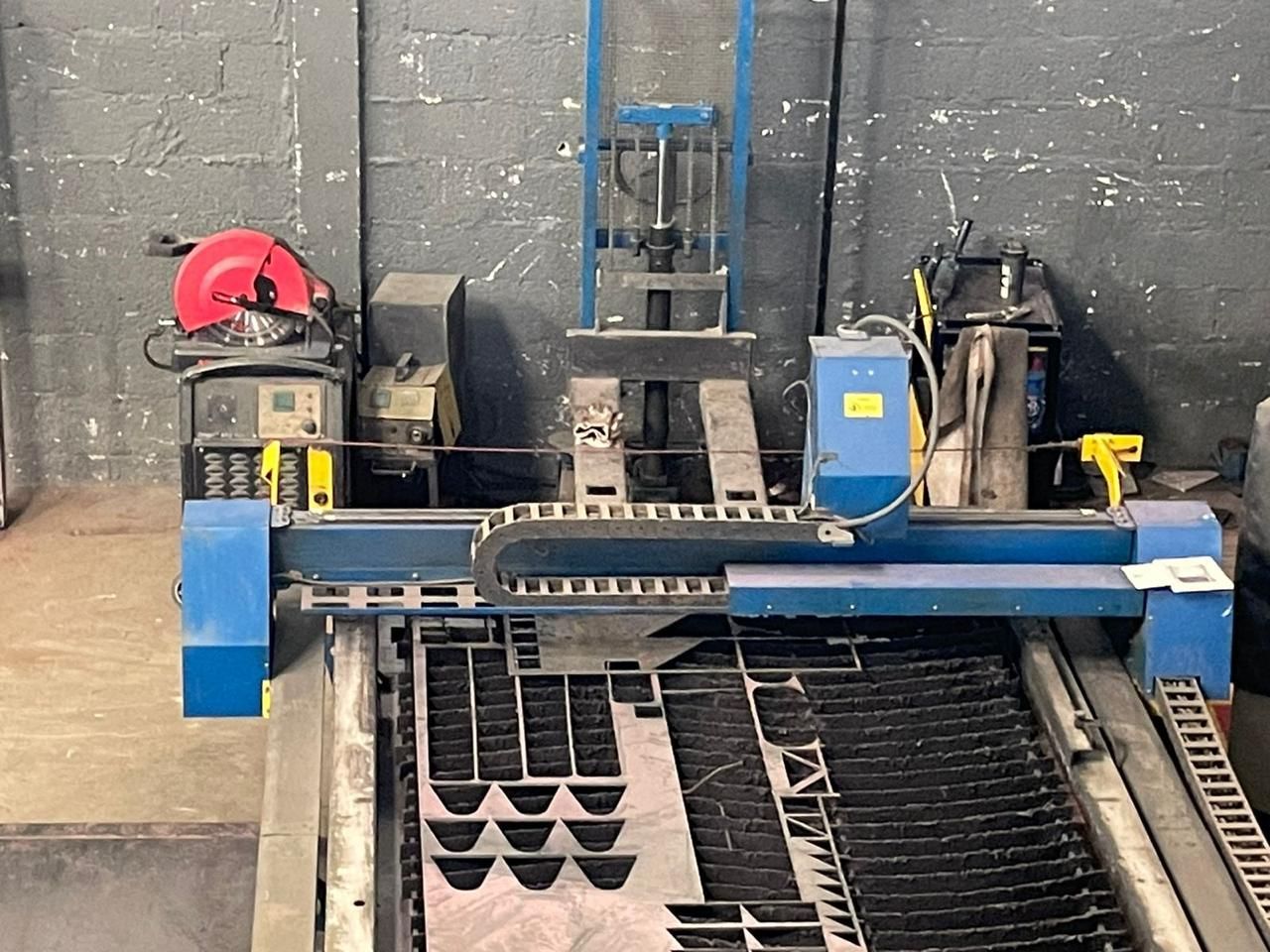 Uma máquina está cortando um pedaço de metal em um armazém.