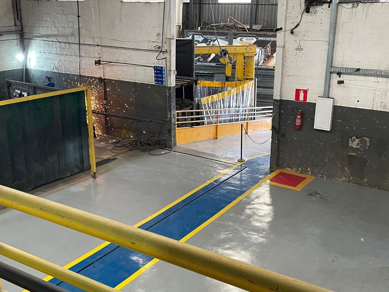 Uma vista aérea de um armazém com linhas azuis e amarelas no chão.