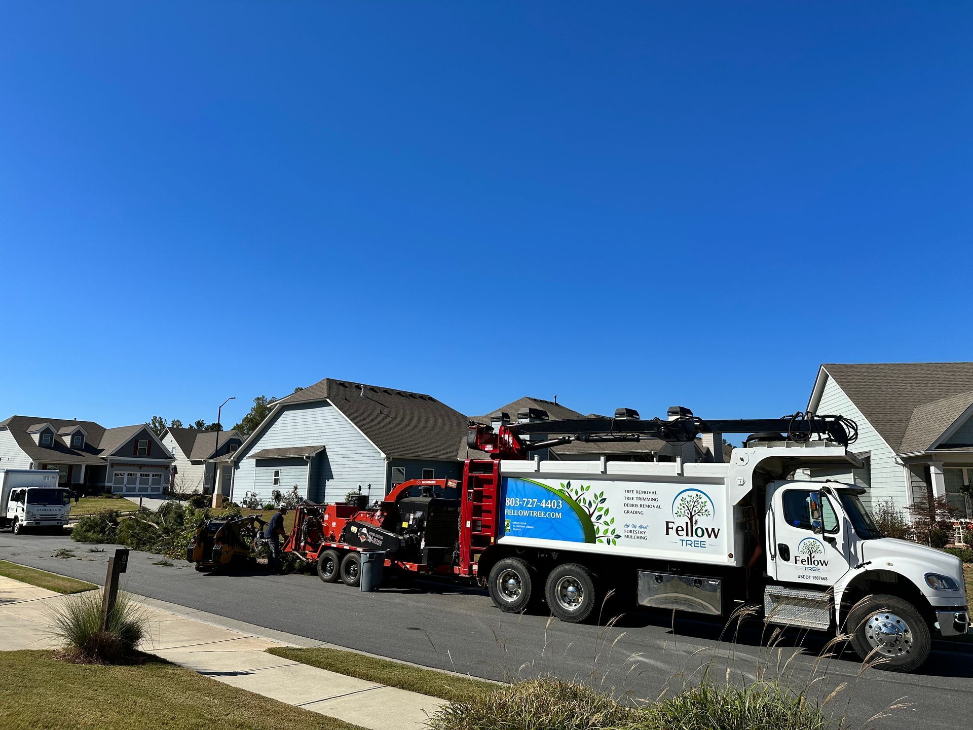 A vacuum truck is parked on the side of the road in front of a row of houses.
