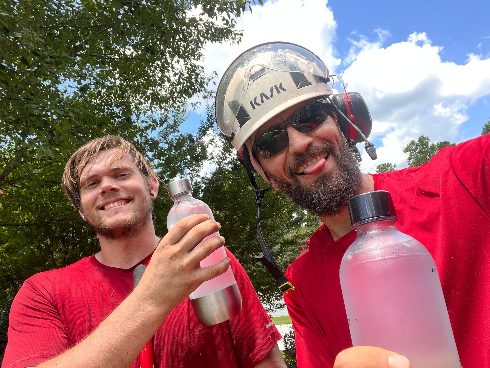 Two men are standing next to each other holding water bottles.