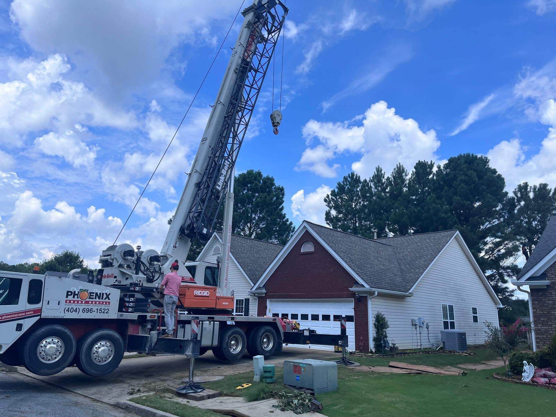 A large truck with a crane attached to it is parked in front of a house.