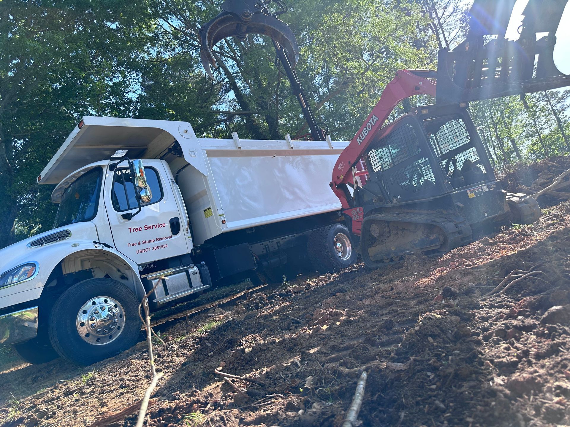 A dump truck is driving down a dirt hill with a crane attached to it.