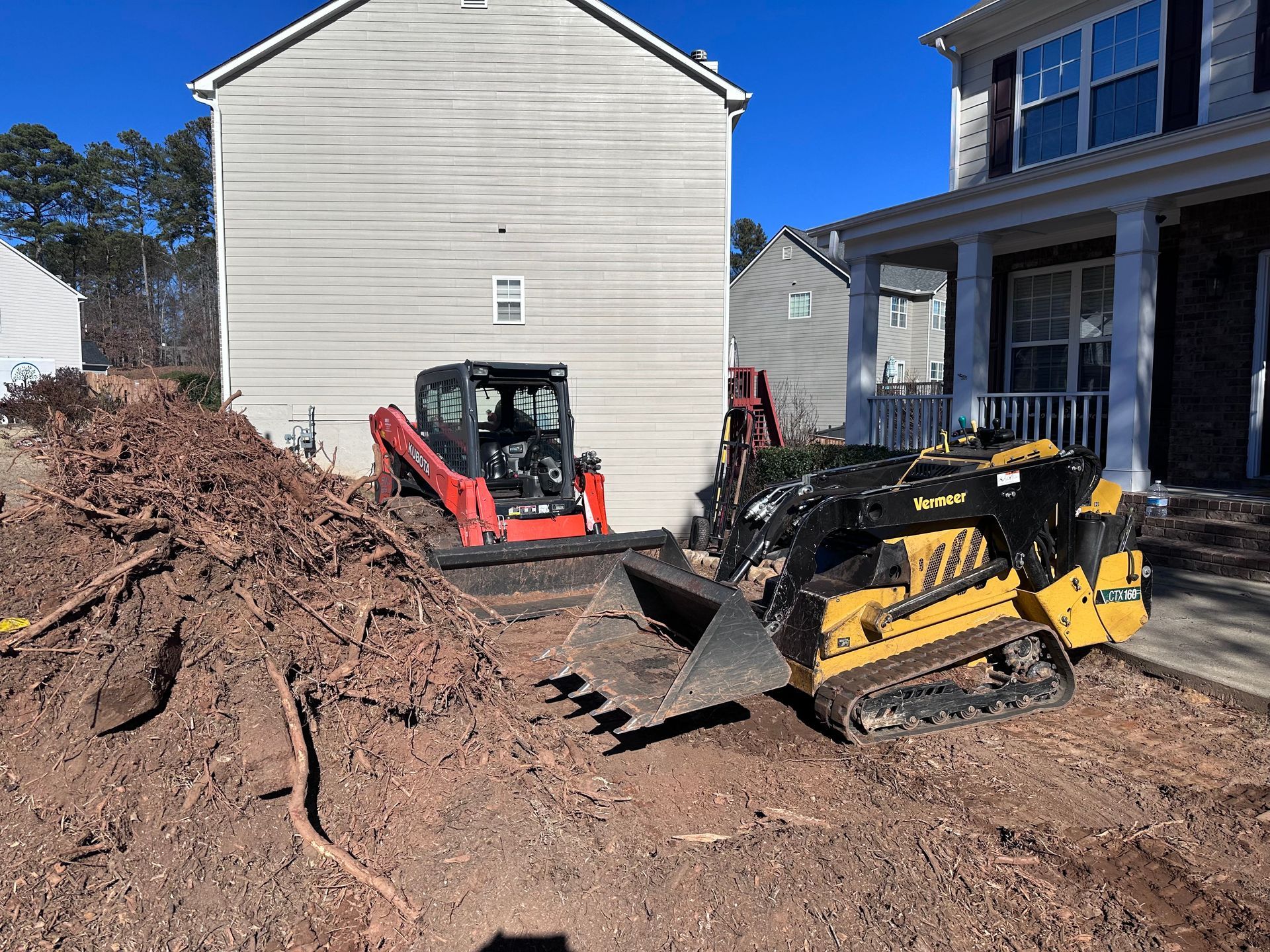 A bulldozer is sitting in front of a house next to a pile of dirt.