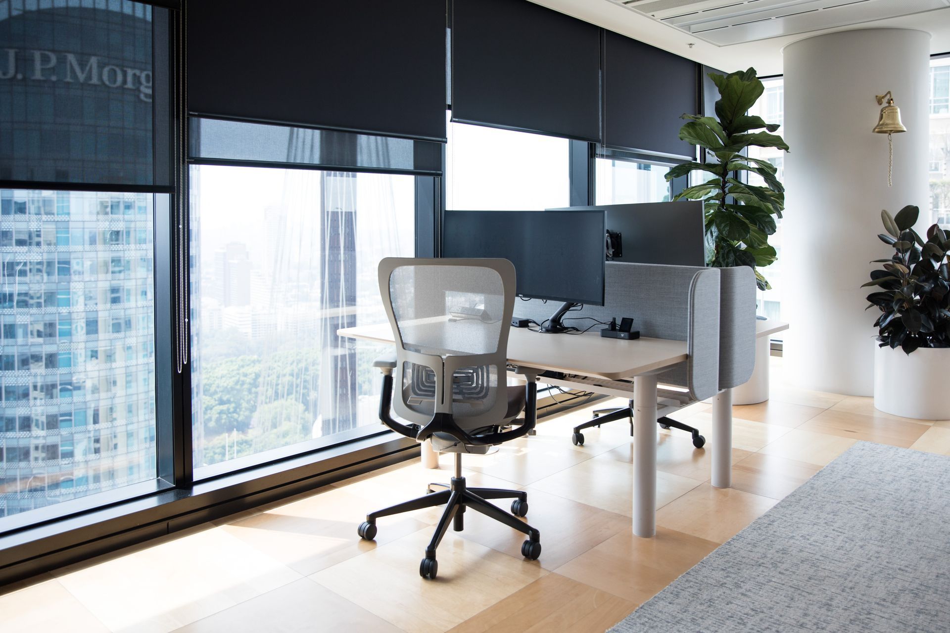 Modern office with a white desk, mesh chair, large windows, and city view Modern office with a white desk, mesh chair, large windows, and city view