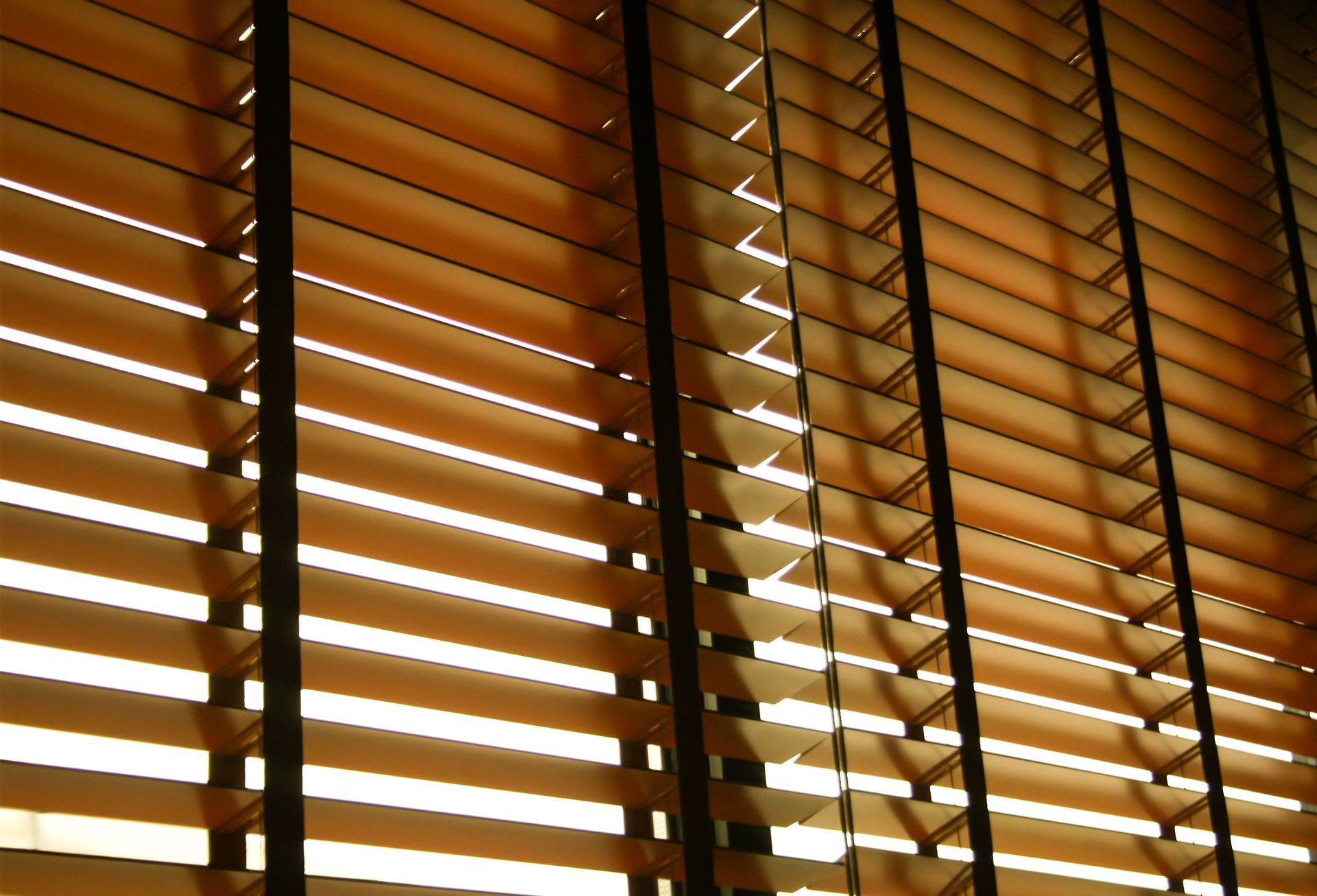 Wooden window blinds with warm sunlight filtering through slats