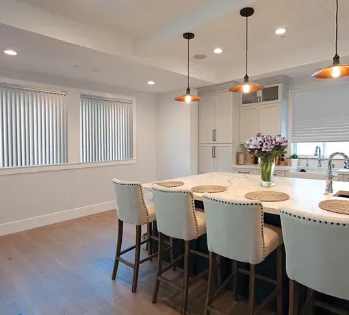 Modern kitchen with a large island, pendant lights, and a dining area with tall chairs