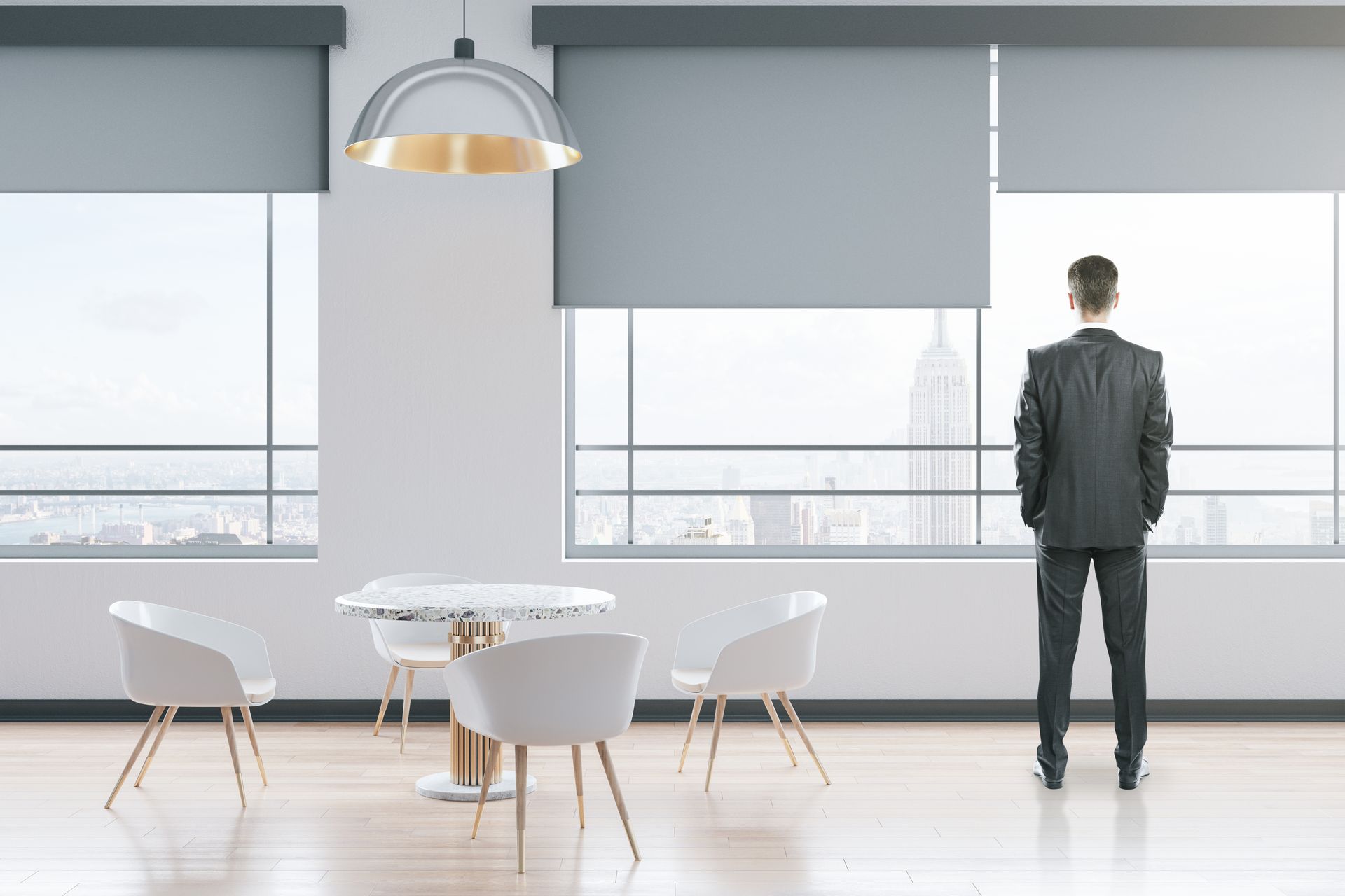 Person standing in a bright modern office, looking out large windows beside a round table and chairs Person standing in a bright modern office, looking out large windows beside a round table and chairs