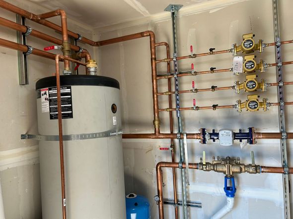 Copper pipes, water heater, and valves installed in a utility room.