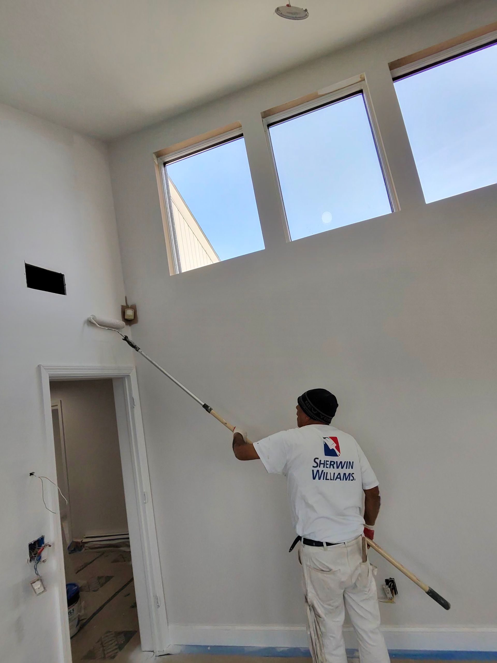 Paint roller applying white paint to a wall.