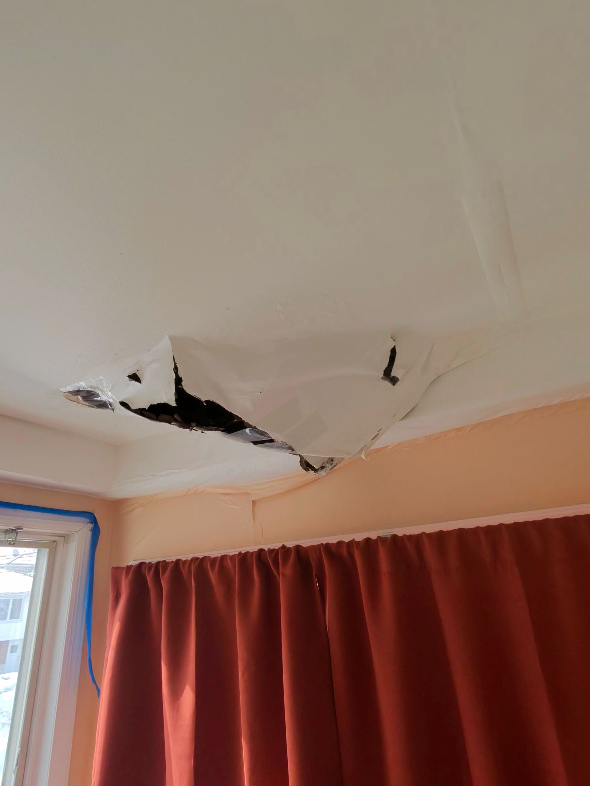 Hands holding mesh patch over a damaged wall, preparing for repair.